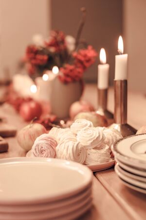 Autumn table decoration for Holiday Thanksgiving dinner. Cozy warm natural style with zephyr marshmallow sweets, candles lights, red berries and applesの写真素材