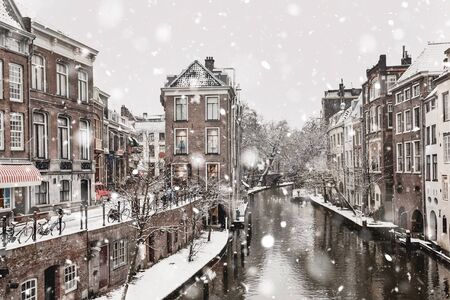 Utrecht The Netherlands in winter snowstorm. Historical buildings along canal in the city center in snowy weather. Magic Christmas mood. Monochromatic neutral tones with natural lightの写真素材