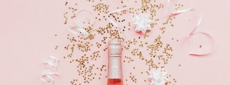 Christmas or New Year composition with bottles of rose champagne and golden shiny sparkle star confetti on pastel pink background, top view. Celebration flat lay. Party creative conceptの写真素材