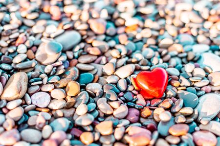 Valentines Day concept. Romantic love symbol of red heart on the pebble beach with copy space. Template for Inspirational compositions and quote postcards.の写真素材