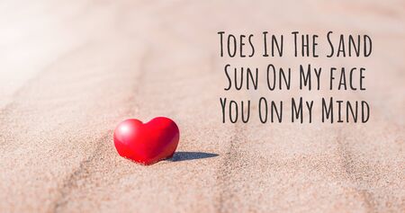 Valentines Day concept. Romantic love symbol of red heart on the sand beach with text message....