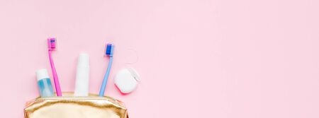 Teeth hygiene and oral dental care products in golden travel cosmetic purse kit pastel pink color background with copy space. Blank tube of toothpaste and toothbrushes. Flat lay, top view compositionの写真素材