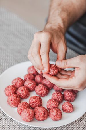 Man hands preparing meatballs with raw mincemeat. Lifestyle close up composition with natural light....