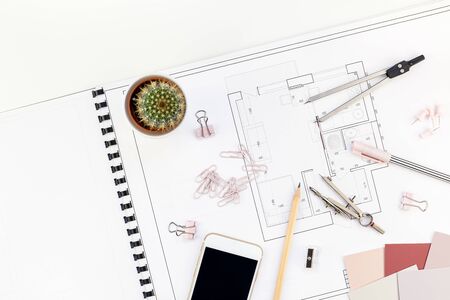 Blueprint flat project plan and office supplies on decorator table workspace. Swatches, tools, smartphone device and equipment background with copy space. Creative flat lay overhead top view conceptの写真素材