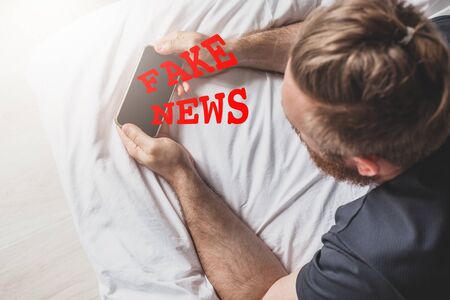 Fake news infodemics during Covid-19 pandemic concept. Man hands holding mobile phone reading global...