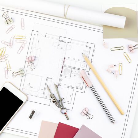 Blueprint flat project plan and office supplies on decorator table workspace. Swatches, tools, smartphone device and equipment background with copy space. Creative flat lay overhead top view conceptの写真素材