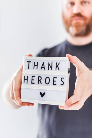 Nurse day concept. Man hands holding lightbox with Thank heroes text thanking doctors, nurses and medical staff working in hospitals during coronavirus COVID-19 pandemics.の写真素材