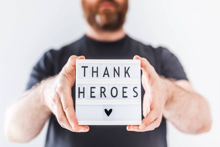 Nurse day concept. Man hands holding lightbox with Thank heroes text thanking doctors, nurses and medical staff working in hospitals during coronavirus COVID-19 pandemics.の写真素材