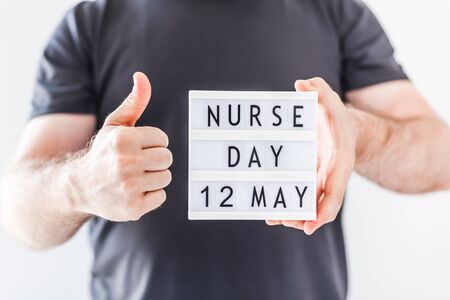 Nurse day concept. Man hands holding lightbox with text Nurse day 12 May thanking doctors, nurses and medical staff working in hospitals during coronavirus COVID-19 pandemicsの写真素材