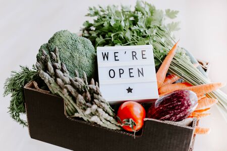 End of quarantine lockdown. Lightbox with greeting text message We're open and Fresh greens and vegetables box. Welcoming grocery shop clients after coronavirus Covid-19 pandemic outbreakの写真素材