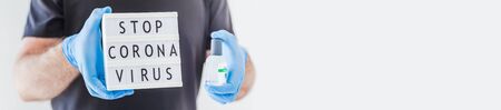 Hand sanitizer hygiene alcohol gel bottles and lightbox with text Stop Coronavirus in hands of man wearing latex medical gloves and protective mask during coronavirus COVID-19 pandemics. Healthcareの写真素材
