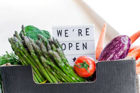 End of quarantine lockdown. Lightbox with greeting text message We're open and Fresh greens and vegetables box. Welcoming grocery shop clients after coronavirus Covid-19 pandemic outbreakの写真素材