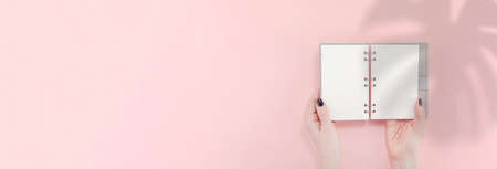 Creative flat lay top view of woman hands black manicure with empty notebook mock up on pastel millennial pink paper background copy space. Minimal writing concept template for text lettering bloggingの写真素材