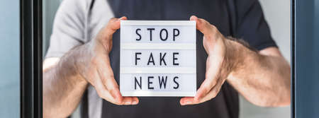 Fake news infodemics during Covid-19 pandemic concept. Man hands holding lightbox with text Stop...