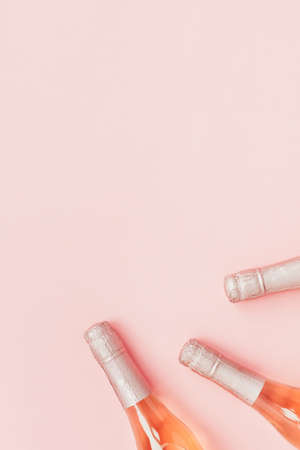Bottle of rose champagne wine in minimal composition on pink background with copy space. Natural light. Template for tasting, degustation invitation card. Top view. Flat layの写真素材