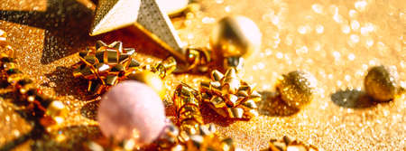 Christmas composition. New Year or Christmas pattern flat lay top view Xmas holiday celebration sparkling golden decoration on golden background with copy space. Template of greeting cardの写真素材