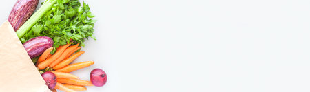 Fresh organic vegetables in eco craft paper shopping bag in flat lay, top view with copy space on gray background. Sustainable lifestyle. Zero waste, plastic free, care package, donation conceptの写真素材