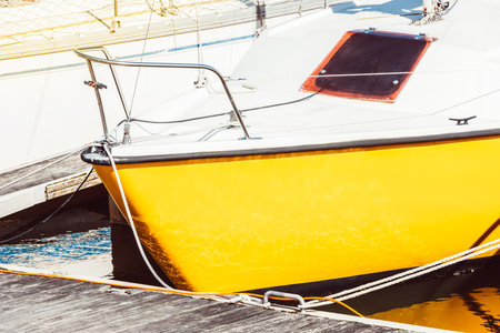 Yellow sailboat moored at marina dock with sunlit reflections, background,の写真素材