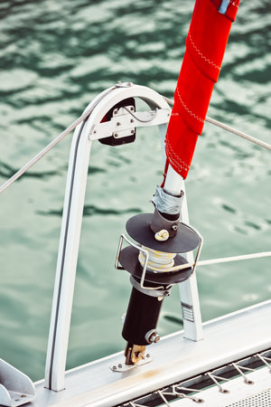 Sailboat rigging and red sail detail against water background,の写真素材