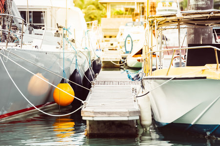 Boats moored at marina with floating dock and ropes, summer travel destination,の写真素材