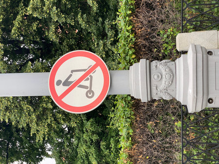 No scooters sign against green foliage background on city street light postの写真素材