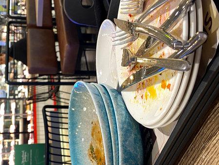 Empty plates with leftover food and utensils on a tray in a restaurant settingの写真素材