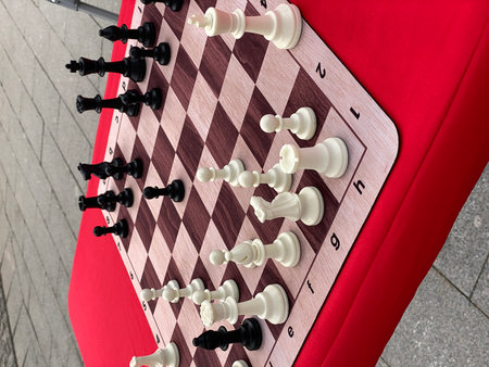 Chess board with pieces on outdoor table, red tablecloth, background for strategic conceptsの写真素材