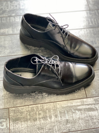 Black leather shoes on wooden floor, top view for footwear fashion concept or background. Mobile...