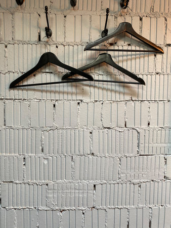 Empty hangers on textured brick wall background with copy space for fashion or retail concept. Mobile photoの写真素材