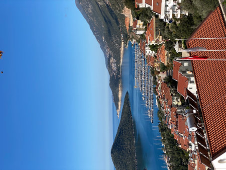 Aerial view of coastal town with marina and red-roofed buildings under clear blue sky. Mobile photoの写真素材