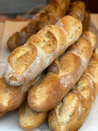 Freshly baked baguettes stacked in close-up, showing crisp crusts and soft interiors. Mobile photo