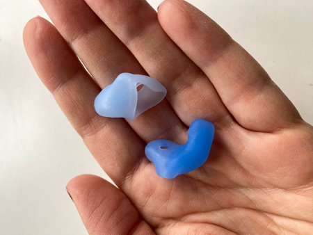 Custom silicone earplugs resting on an open palm, providing noise protection and comfort. Mobile...