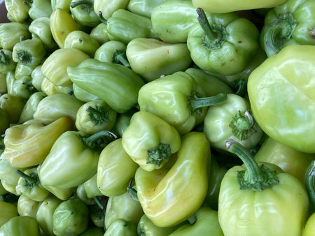 Fresh green peppers piled together creating a vibrant vegetable background. Mobile photo