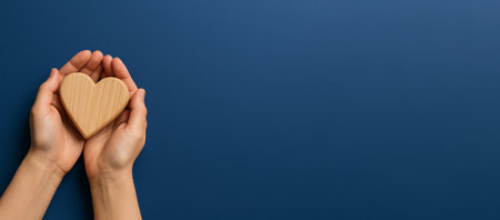 Hands holding wooden heart on blue background, symbolizing charity and care, AI generatedの素材