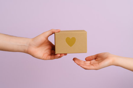 Hands exchanging gift box with heart symbol for Giving Tuesday charity, AI generatedの素材