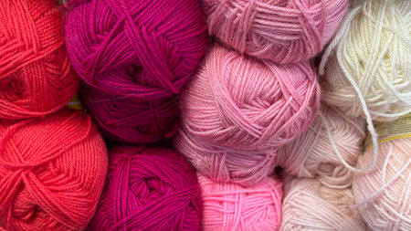 Colorful skeins of yarn in red, pink, and white, arranged side by side for knitting projects. Mobile photoの写真素材