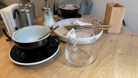 Coffee shop table with empty cups and crockery showcasing post-meal setting with utensils. Mobile photoの写真素材