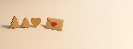 Wooden Christmas tree, bell, heart, envelope on beige background, holiday concept, AI generatedの素材