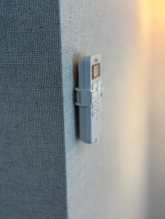 Remote control mounted on textured wall with soft light in background offering a modern aesthetic.