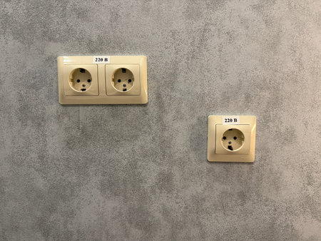 Electrical wall sockets on textured concrete wall background with space for copy or design. Mobile...