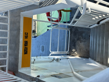 Staircase on ship deck with watch your head sign and safety equipment in bright sunlight. Mobile...