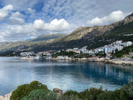 Coastal town with mountainous backdrop under cloudy sky, perfect for travel background or adventure. Mobile photoの写真素材