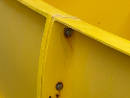 Yellow industrial metal surface with rusty bolts, suitable for backgrounds or abstract concepts....
