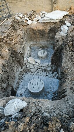 two concrete circle pole in dig out of hole for make foudation pile near wall. Building house in construction site. Reinforcement with rebar cubic square blockの写真素材
