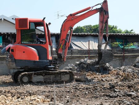 small orange excavator or macro truck working in house construction siteの写真素材