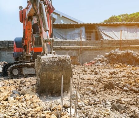 small orange excavator or macro truck digging soil for build foundation pile in construction siteの写真素材