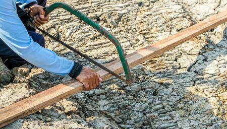 carpenter man use saw cut wooden plank build houseの写真素材