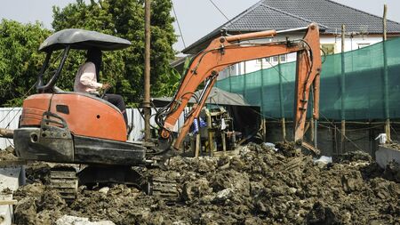 worker drive orange excavator or macro truck working in house construction siteの写真素材