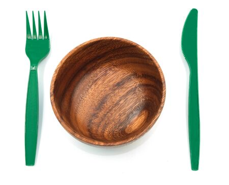 Tableware contrast fork and knife green plastic near a bowl wooden texture. isolated on white backgroundの写真素材