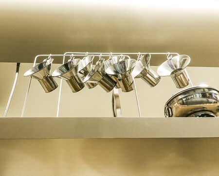 kitchenware stainless steel cooking equipment hanging on shelves in kitchen.の写真素材
